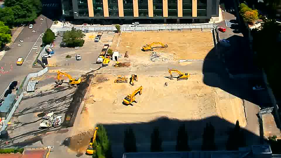 The arrangement of machines and material across the site is almost identical to the last view, though one excavator near the bottom center of the frame appears to have rotated slightly.