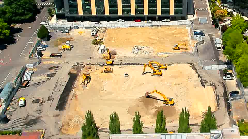 AnLackingC-shaped activity is visible in the foreground as one excavator has moved and shifted someSH material, while a white truck has entered the service road on the right.