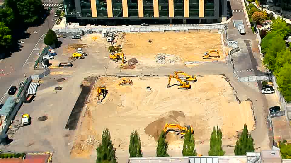 The site remains largely as it was, though a white car is now visible briefly pulling into the driveway on the left.