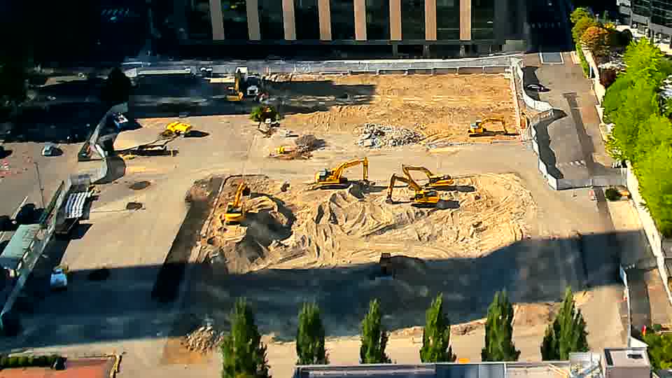 The scene remains largely unchanged, with the positions of the heavy equipment and material piles appearing consistent.