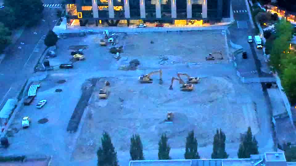 The site is now visible in daylight, revealing several pieces of heavy equipment positioned across the graded area. Conditions appear quiet with no noticeable movement of machinery or vehicles between the frames.