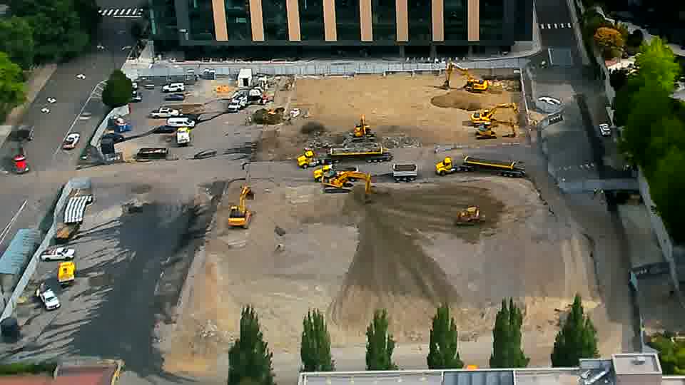 The scene remains largely consistent, though one of the excavators near the center of the site has slightly altered its orientation.