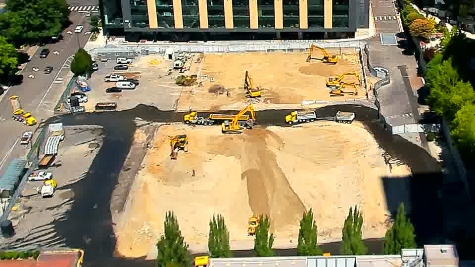 The excavator previously near the center of the frame has rotated, now facing more directly toward the lower-left corner.