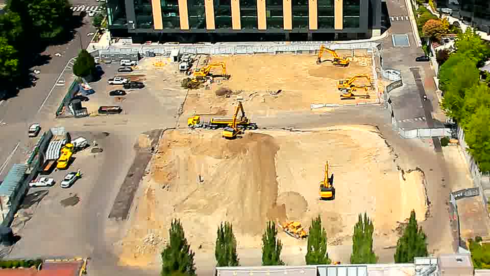 The excavator previously in the lower-center of the frame is now slightly further to the right.