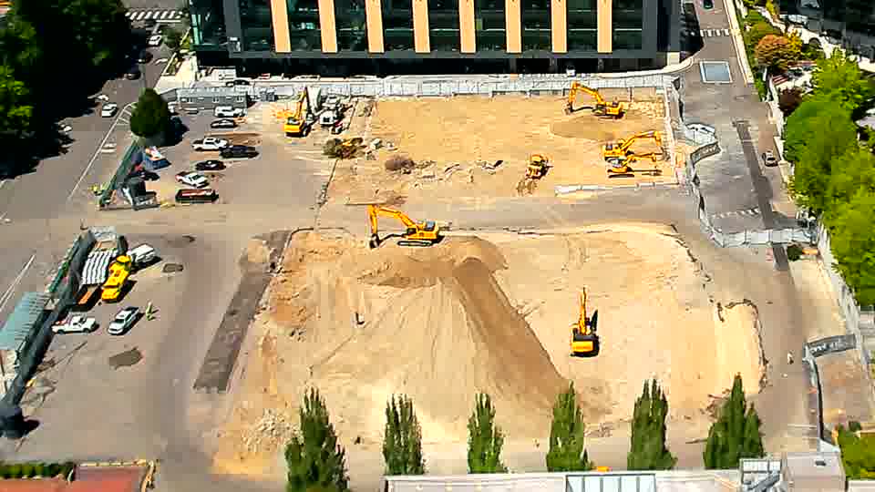 The machines on site hold their positions, with only subtle changes in the play of light across the graded area.