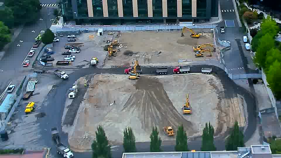A dump truck has entered the site from the left driveway and is now parked near the center of the work area.