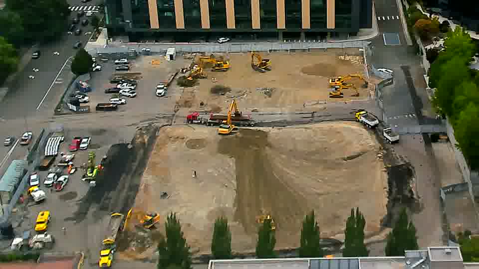 Equipment positions across the site appear nearly identical to the previous view, though a white pickup truck has entered the site via the driveway on the left.
