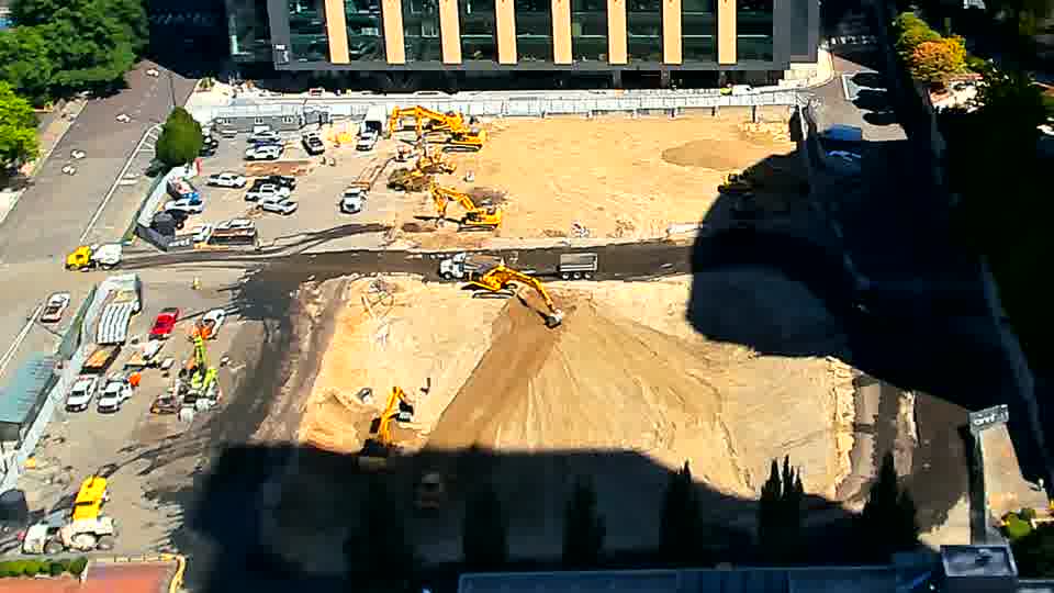 One of the excavators closer to the center of the site has clearly moved forward, and appears to be working a new area. Otherwise, the arrangement of equipment and vehicles remains consistent.