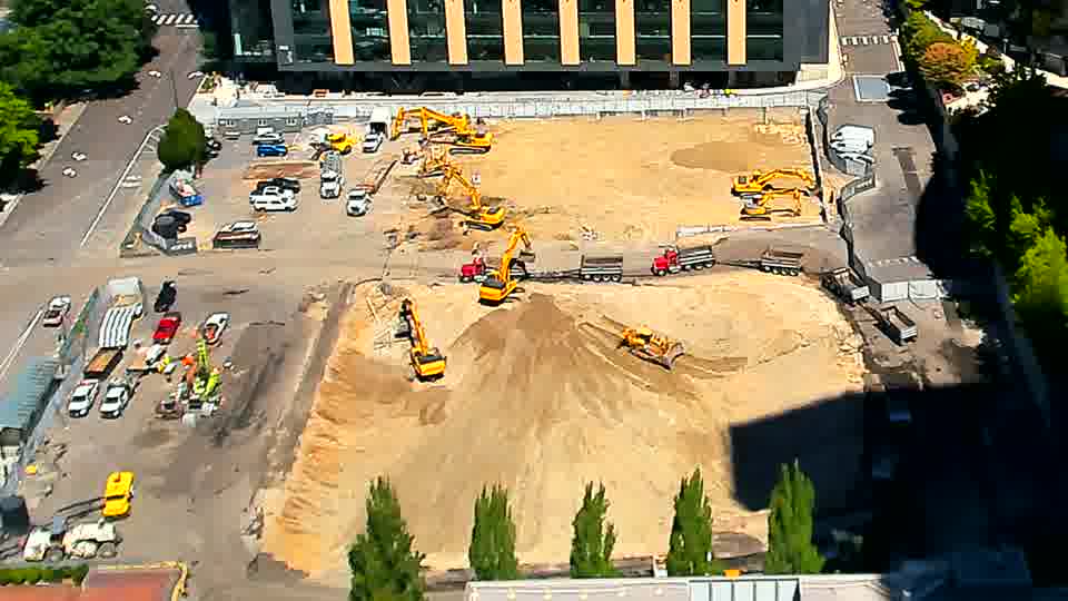 A red and black truck has entered the site via the driveway on the left and is positioned near the center.