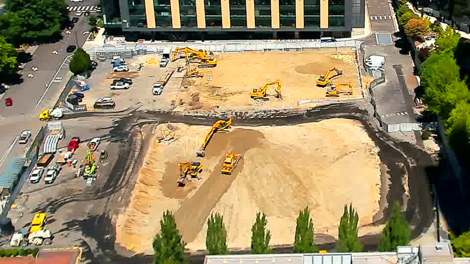 The excavator closest to the bottom of the frame has shifted its position slightly, now angled a bit more towards the center of the site.