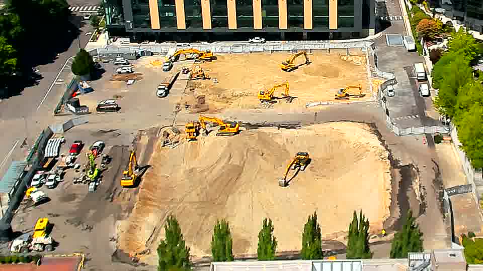 The arrangement of the heavy equipment remains consistent, though one excavator near the bottom of the frame appears to have shifted its position slightly.