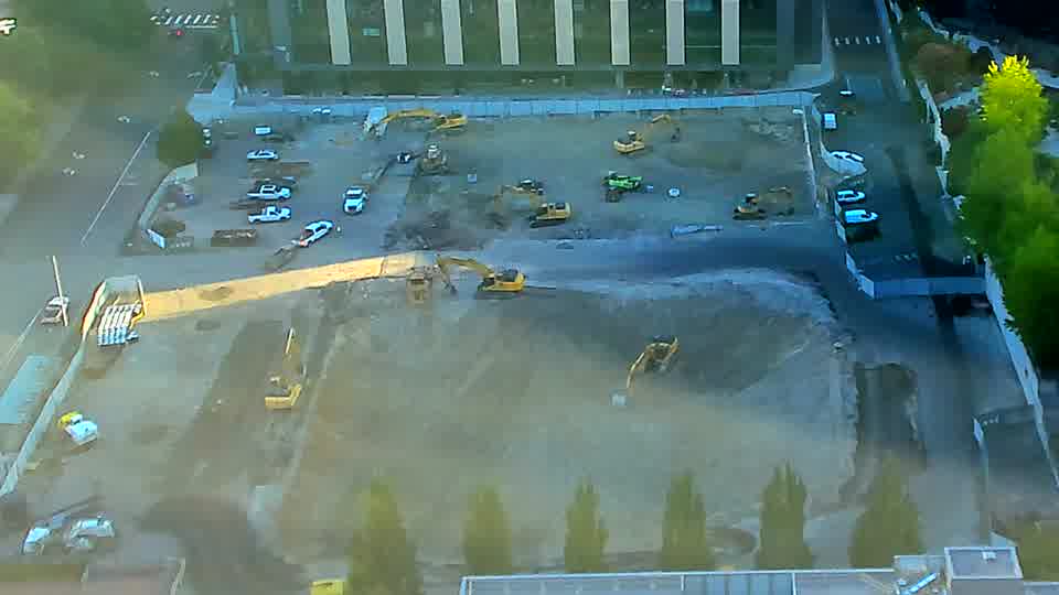 The arrangement of machinery across the site remains consistent, though a small white vehicle has appeared near the bottom of the frame.
