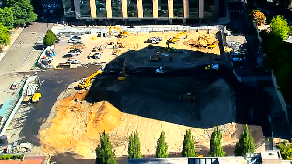 The sun's angle has altered the shadows across the site, but the placement of equipment and materials appears consistent between the views.