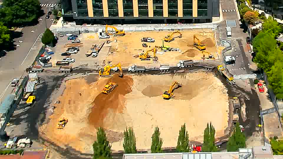 The arrangement of equipment on the site remains consistent, with no discernible alterations in the positions of the machines or stockpiled materials.