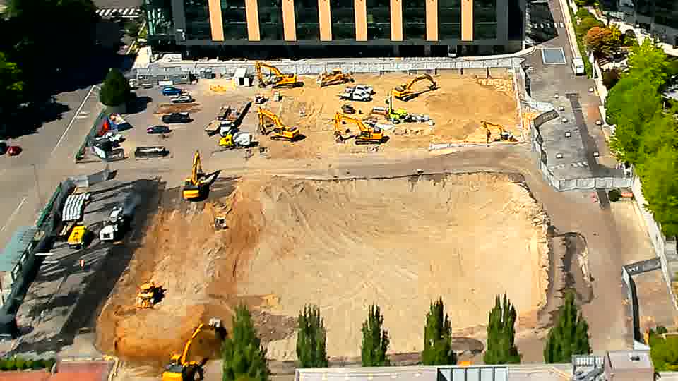 A few figures are now visible near the center of the site, though the machinery positions have not altered.