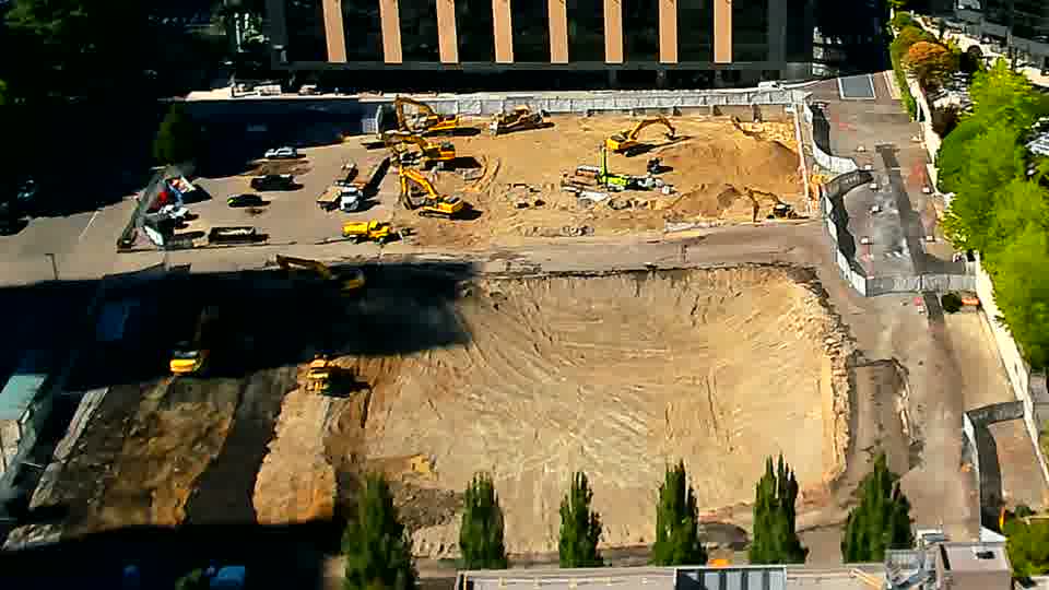 An orange utility vehicle has appeared near the right edge of the site, having not been present in the previous view.
