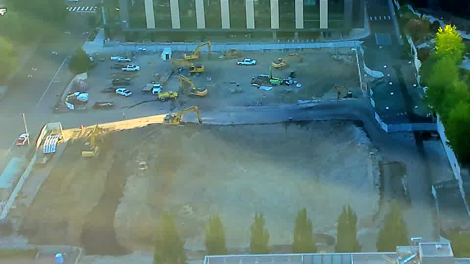 A large yellow machine has rotated its boom toward the lower-right corner of the site. Otherwise, the positioning of equipment across the area appears to be the same as before.