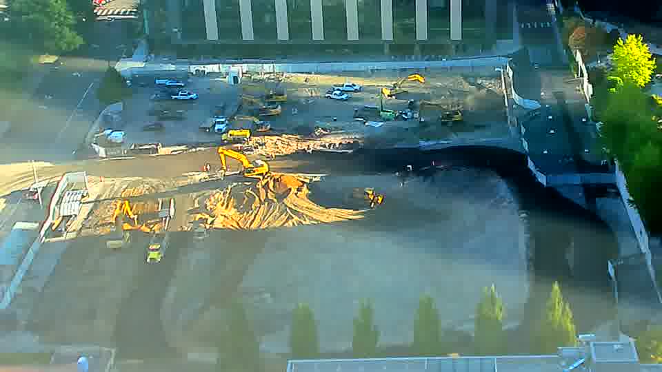 The yellow machine in the lower-left has shifted its position and is now actively working in a different area of the site. Otherwise, the arrangement of equipment across the block appears consistent.
