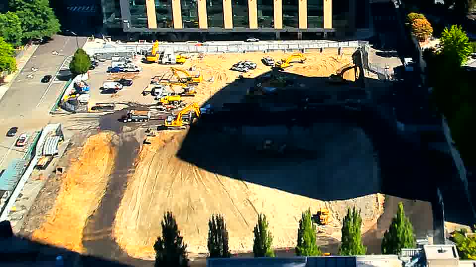The shadows have lengthened across the site, but the positions of the machines and materials are largely unchanged from the previous view.