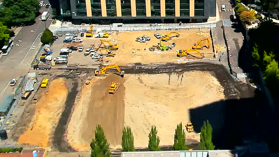 Sunlight continues to illuminate the site, but the positions of machinery and materials have not noticeably altered.