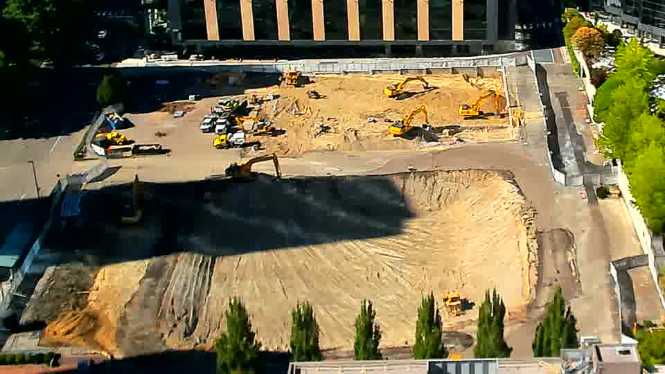 The equipment layout stays consistent, though a small yellow machine is now visible near the lower-right corner of the site.