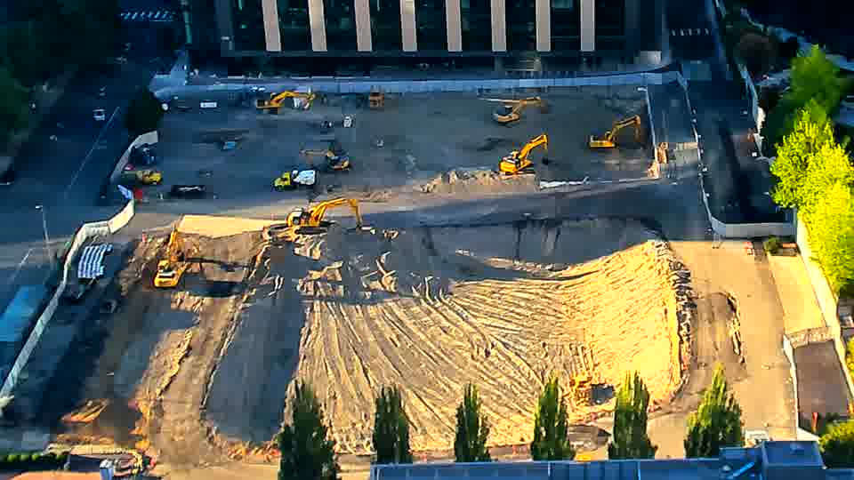 Shadows have lengthened across the graded area, but the layout of equipment remains largely consistent.