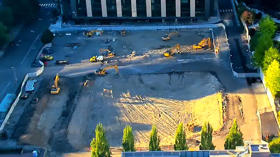 L0: An overhead view of a construction site with several yellow excavators positioned across a dirt lot.
6: One excavator on the left has moved slightly forward, and another in the center has shifted its position.