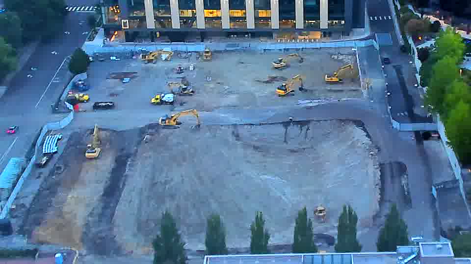 The equipment arrangement appears largely unchanged, though a yellow machine has shifted slightly further into the center of the site.