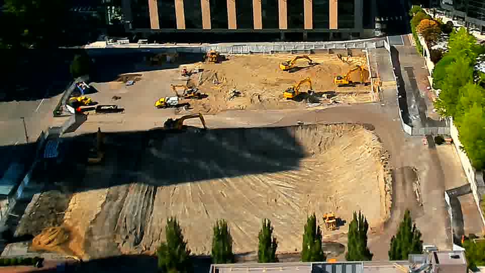 A small earthmoving machine has shifted position within the graded area near the center of the site. Otherwise, the scene appears consistent, with the larger equipment remaining in the same locations.