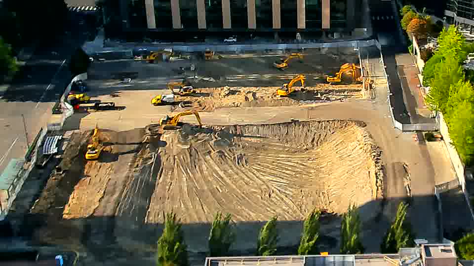 The scene is remarkably unchanged, with all visible machinery and stockpiles holding their positions.