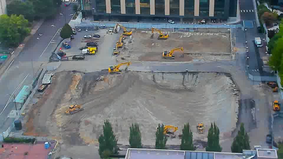 The layout of machinery across the site is stable, though the light has subtly altered the appearance of the graded area.