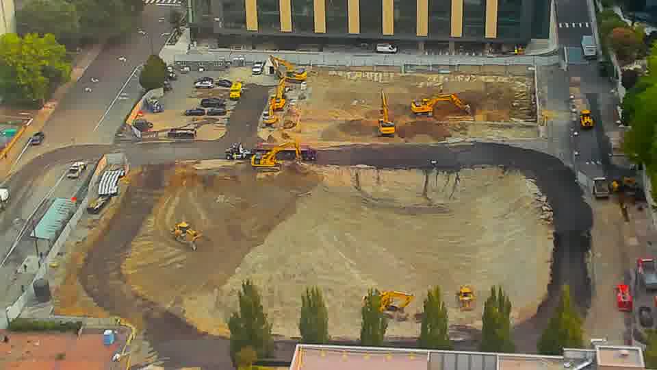 The arrangement of the machinery across the site remains consistent, though one of the excavators near the center has subtly shifted its position.