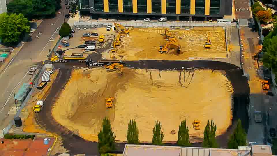 A small orange vehicle has appeared near the lower-right corner of the site, having not been visible in the previous frame.