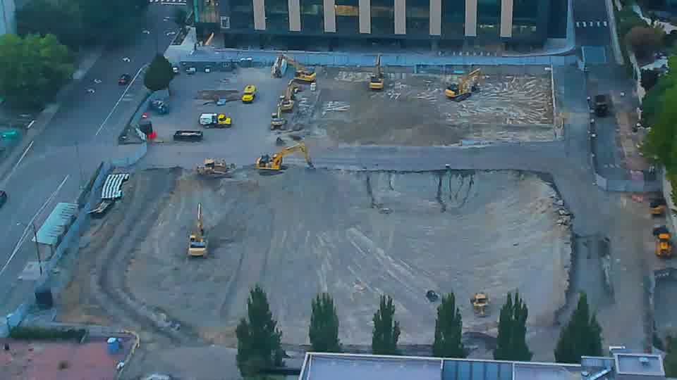 The overall layout of the site remains consistent, though a dark-colored vehicle has entered the driveway on the left side of the frame.