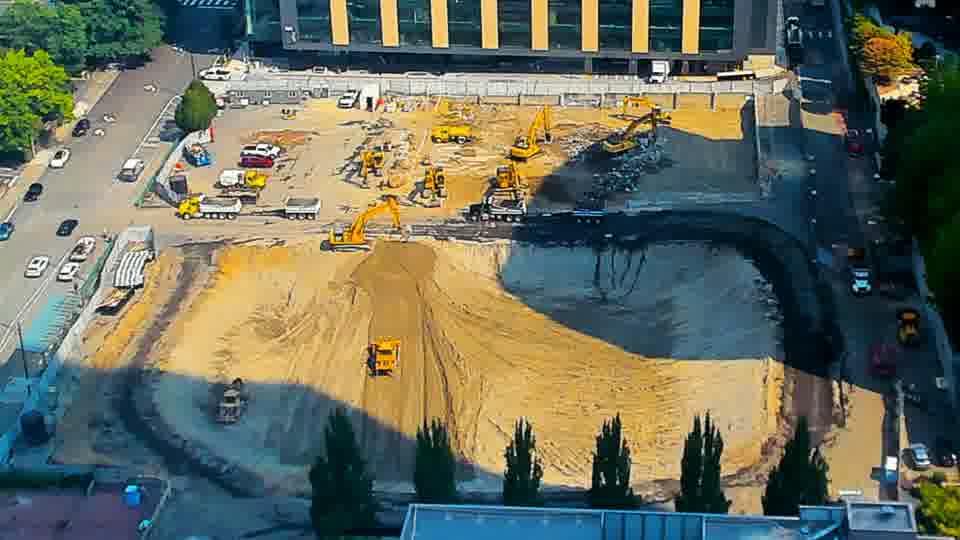Two white trucks have arrived at the drivewayL-shaped driveway on the left, and a piece of equipment has shifted positionC position in the southern area.