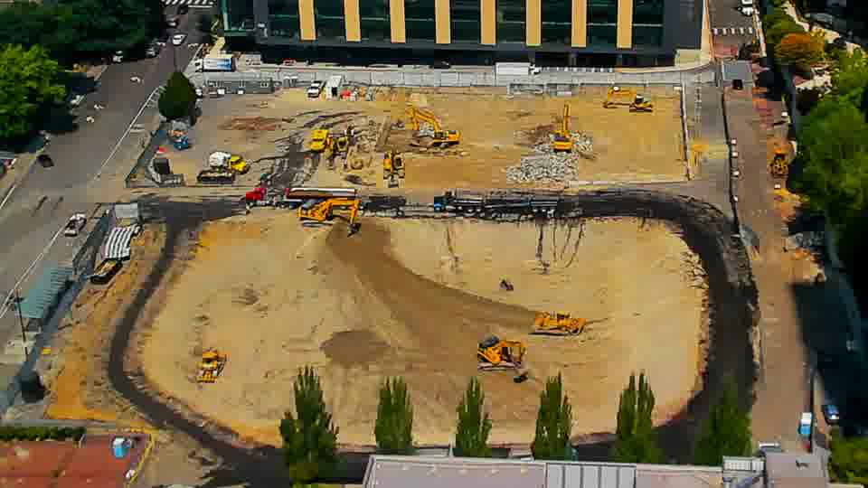 The worked area near the lower-right corner now includes a small yellow machine that wasn't present in the earlier view. Beyond that, the scene holds a similar arrangement of equipment and materials.