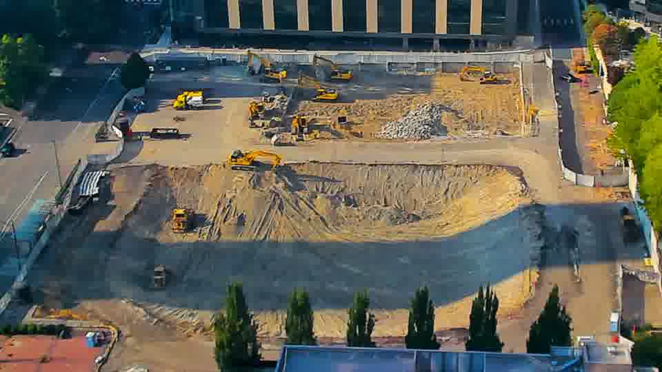 The arrangement of machines and stockpiled materials appears static, though shadows have shifted with the sun.