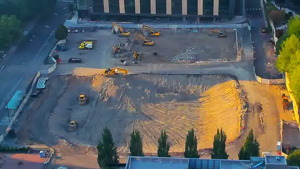 A small, yellow piece of equipment has moved slightly further into the graded area near the center of the site.