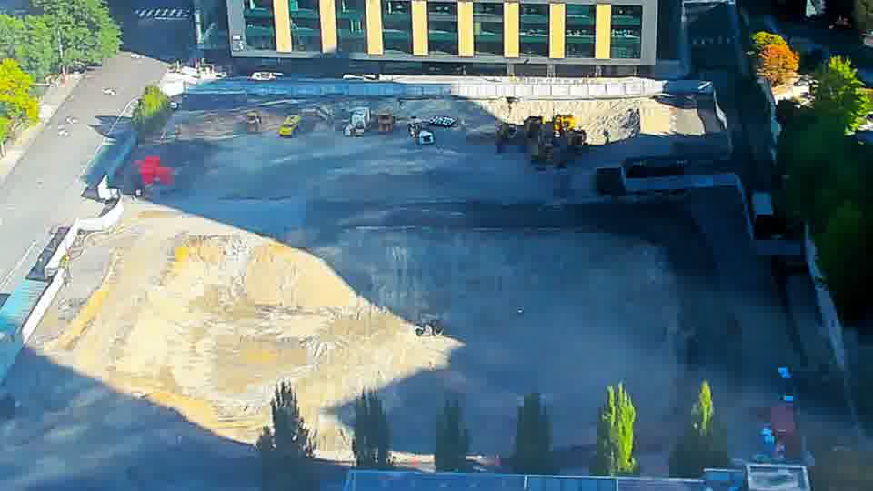 Construction camera frame at 10:00 AM PT. The site holds steady, with all visible machines and materials maintaining their previous arrangement.