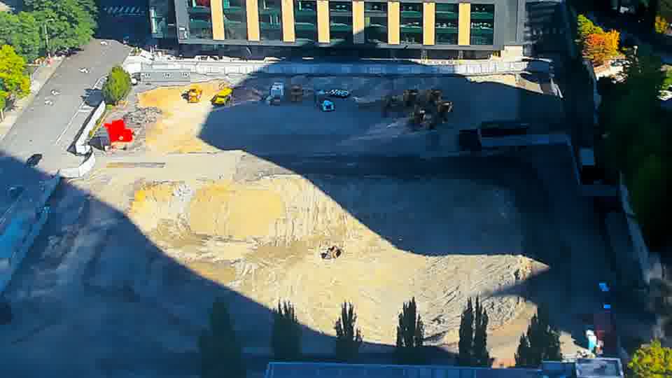 Construction camera frame at 10:30 AM PT. The arrangement of equipment appears largely the same, though a small, light-colored object is now visible near the center of the graded area.