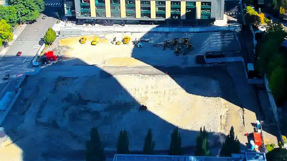 Construction camera frame at 11:00 AM PT. The scene appears remarkably still, with no discernible shifts in equipment or material placement across the site.