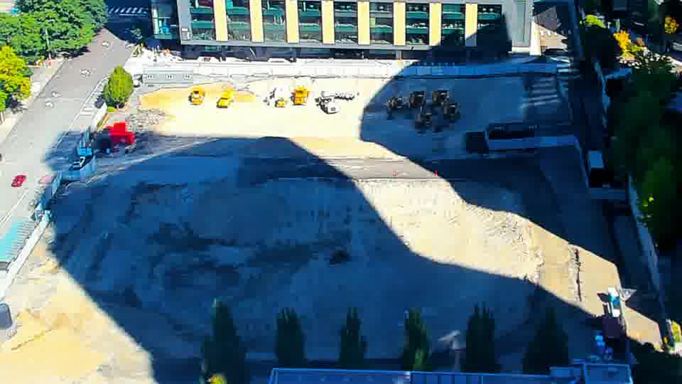 Construction camera frame at 11:15 AM PT. The shadows have shifted slightly across the graded area, but the equipment and materials remain in the same positions.