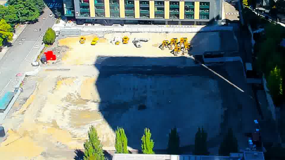 Construction camera frame at 11:45 AM PT. The scene remains largely static, with the equipment and materials holding their previous positions under the lengthening shadows.