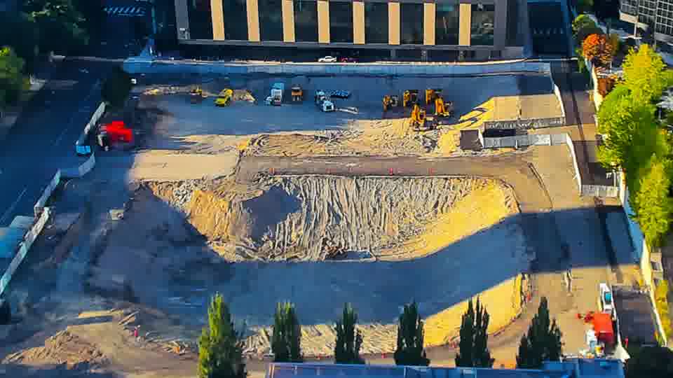 Construction camera frame at 6:15 PM PT. The scene appears largely still, with equipment maintaining its previous arrangement across the site.