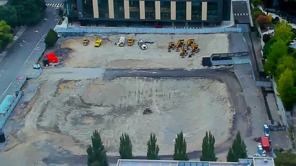 Construction camera frame at 9:15 AM PT. The scene is quiet, with all machinery and vehicles maintaining their previous locations.