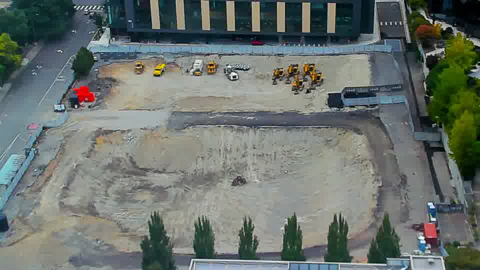 Construction camera frame at 10:00 AM PT. The site presents a static view, with all visible equipment holding its prior position.