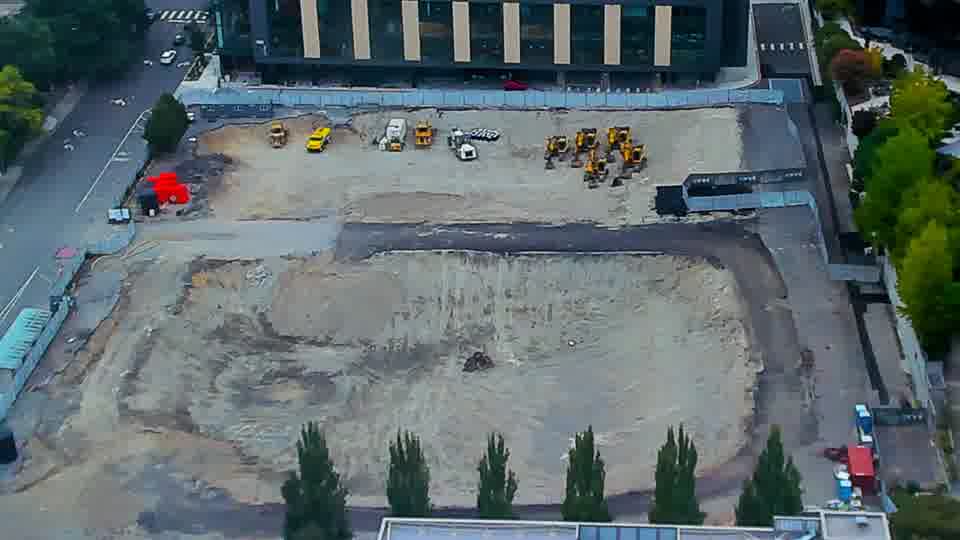 Construction camera frame at 11:00 AM PT. The scene remains consistent, with all visible machinery maintaining its previous placement.