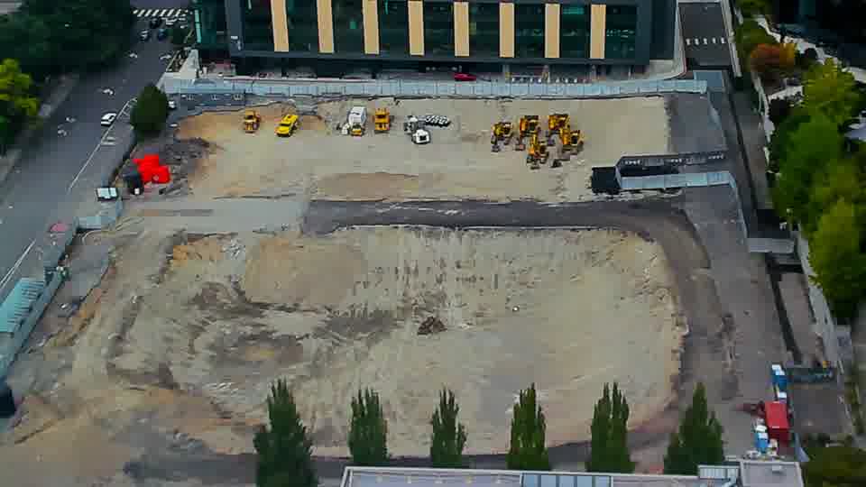Construction camera frame at 12:45 PM PT. The scene maintains a steady state, with all visible machinery and materials holding their prior positions.