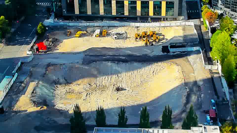 Construction camera frame at 5:15 PM PT. Sunlight now falls across more of the graded area, but all equipment and vehicles appear to be in the same locations as before.