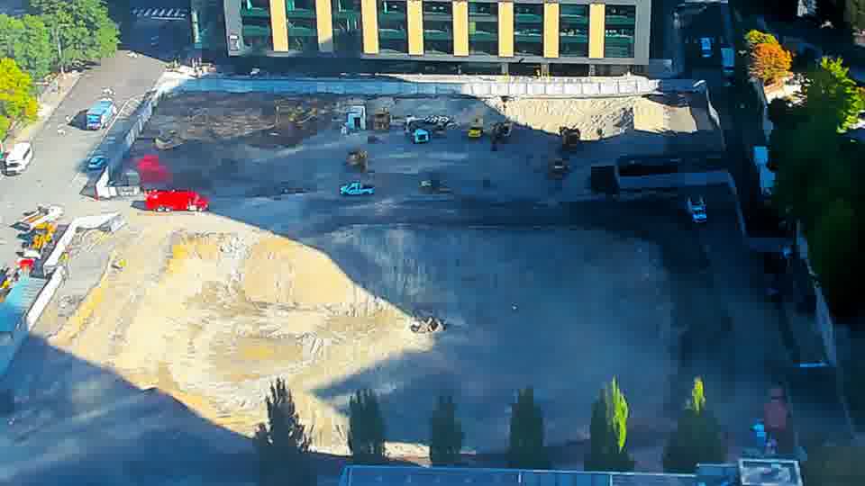 Construction camera frame at 10:00 AM PT. A fire truck has entered the site via the driveway on the left. Otherwise, no visible change between these frames.